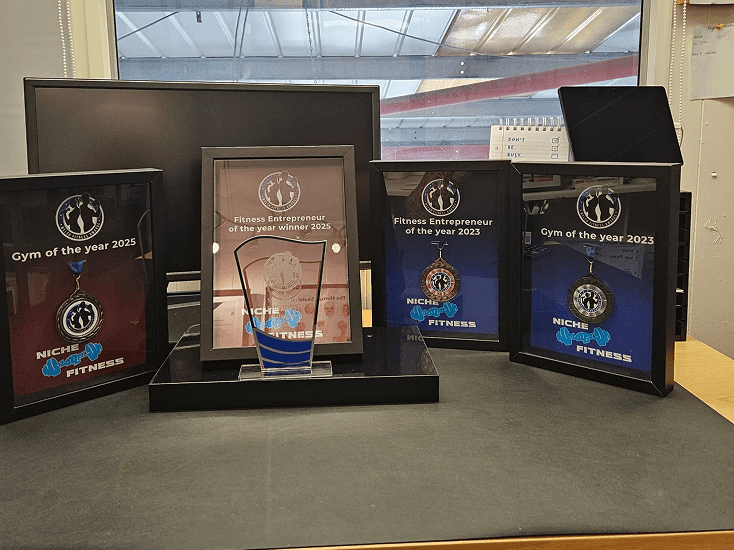 Collection of Niche Fitness Awards displayed on a desk